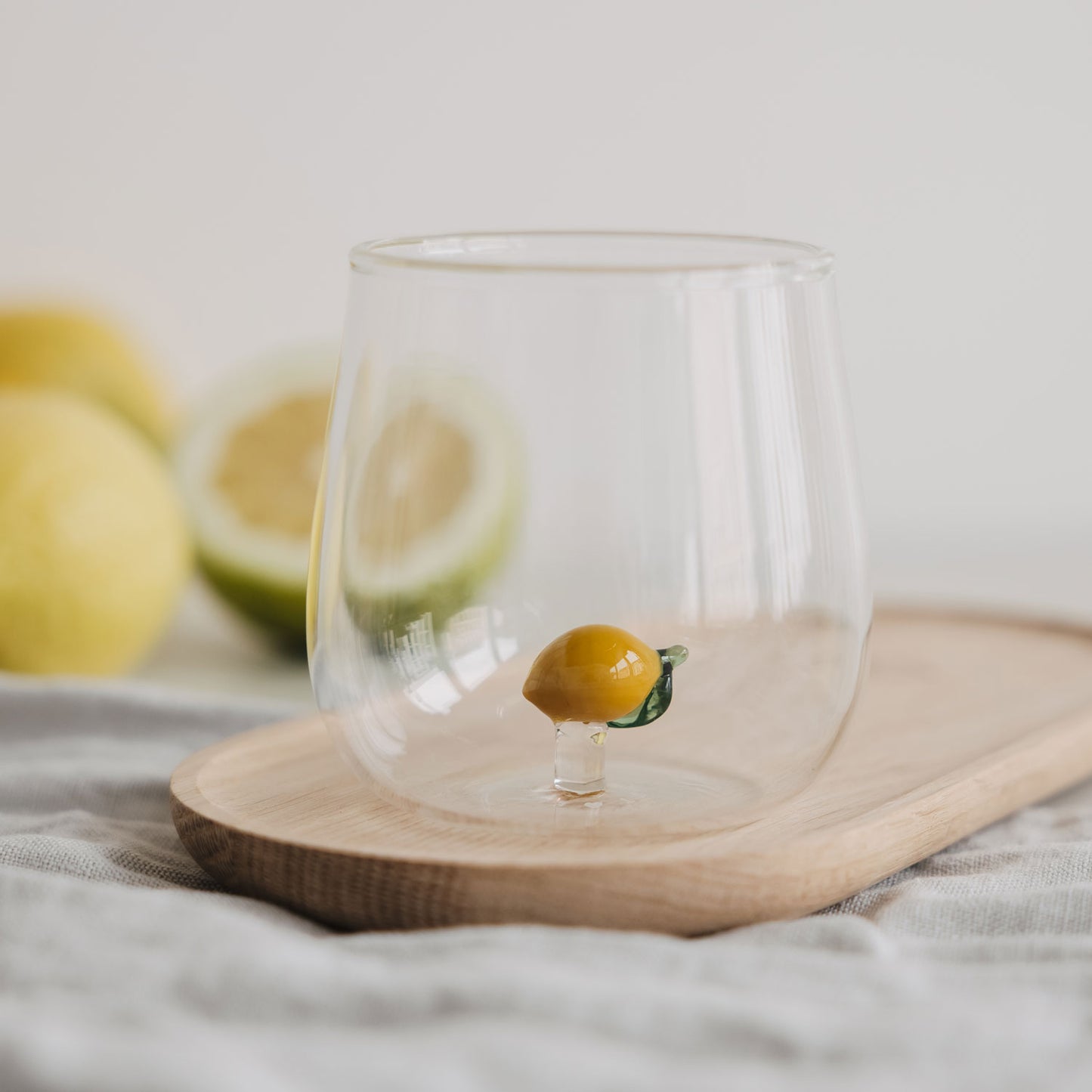 Minimalistisches Trinkglas mit Zitronen Design, klares Glas für Wasser auf Holztablett