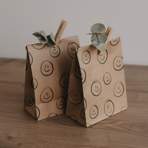 Papiergeschenktüten aus braunem Kraftpapier mit Smileys, modern und verspielt gestaltet